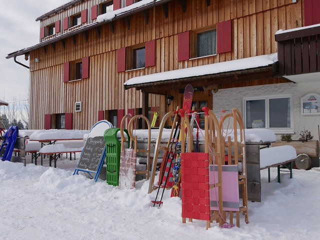 Buronhütte im Winter mit Schlitten und Skiern